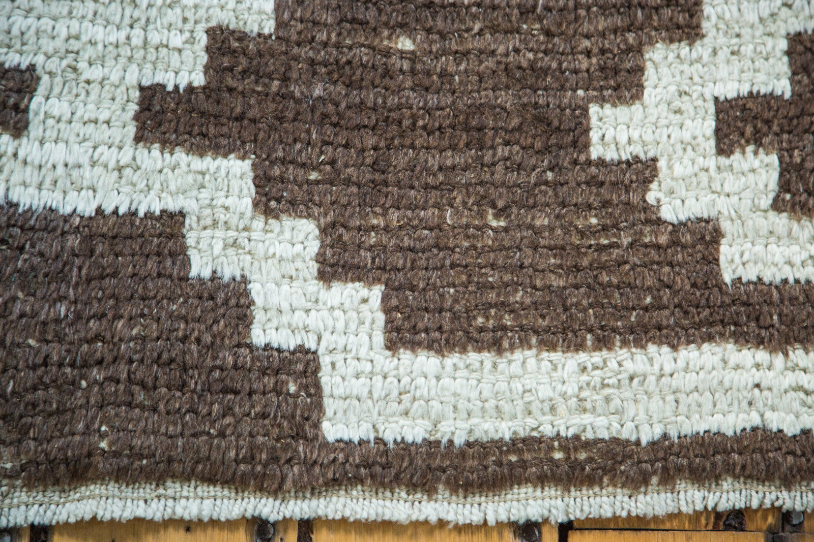 Shaggy pile and geometric pattern of vintage Tulu rug in pale ivory and charcoal.